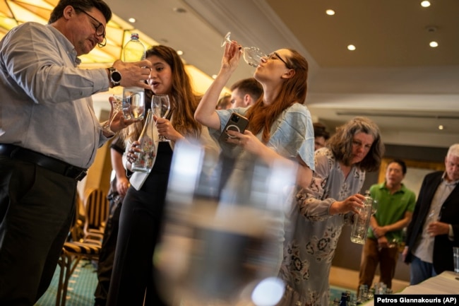 People sample glasses of fine water during an international water tasting competition held in Athens, Greece, on Wednesday, April 26, 2023. (AP Photo/Petros Giannakouris)