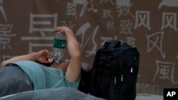 A man drinks a bottle of water as he rests on a bench on a sweltering hot day in Beijing, July 19, 2023.