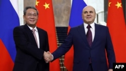 In this pool photograph distributed by the Russian state agency Sputnik, Russia's Prime Minister Mikhail Mishustin, right, shakes hands with Premier of the State Council of China Li Qiang as they meet in Moscow on Aug. 21, 2024.