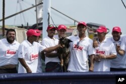 The crew of the Mexican tuna boat "Maria Delia" pose for photos with Bella, the dog of Australian Timothy Lyndsay Shaddock, as they bring the pair to port in Manzanillo, Mexico, July. 18, 2023.