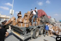 Palestinians pull aid from a truck near the Rafah border crossing in the Gaza Strip, Nov. 2, 2023.