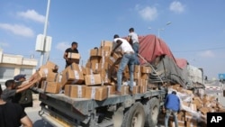 FILE - Palestinians pull aid from a truck near the Rafah border crossing in the Gaza Strip, Nov. 2, 2023.