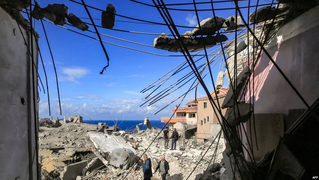 Orang-orang berjalan melewati puing-puing bangunan yang hancur menyusul serangan di kota Naqura di Lebanon selatan dekat perbatasan dengan Israel utara, 4 Januari 2024. (AFP)