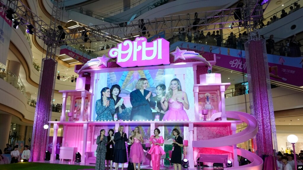 2023 年 7 月 2 日，在韩国首尔举行的电影“芭比娃娃”粉红地毯活动上，大屏幕上显示的亚美莉佳·费雷拉（左）、导演格蕾塔·葛韦格（中）和玛格特·罗比（右）。（美联社照片）(photo:VOA)