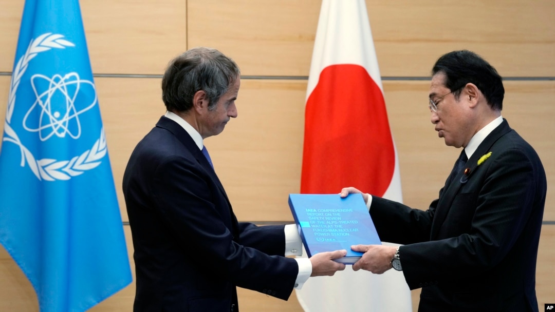 Rafael Grossi, Director-General of the IAEA, left, presents IAEA's comprehensive report on the Fukushima Treated Water Release to Japanese Prime Minister Fumio Kishida, at the prime minister's office, July 4, 2023, in Tokyo.