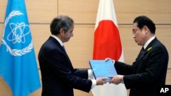 Rafael Grossi, Director-General of the IAEA, left, presents IAEA's comprehensive report on the Fukushima Treated Water Release to Japanese Prime Minister Fumio Kishida, at the prime minister's office, July 4, 2023, in Tokyo.