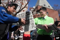 A staff distributes an extra edition of the Yomiuri Shimbun newspaper reporting on Shohei Ohtani to move to the Los Angeles Dodgers Sunday, Dec. 10, 2023, in Tokyo. (AP Photo/Eugene Hoshiko)
