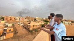 FILE - People watch as smoke rises during clashes between the army and the paramilitary Rapid Support Forces, in Omdurman, Sudan July 4, 2023.