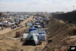 Palestinians displaced by the Israel air and ground offensive on the Gaza Striptake shelter near the border fence with Egypt in Rafah, Jan. 24, 2024.