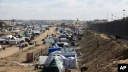 FILE—Palestinians displaced by the Israel air and ground offensive on the Gaza Striptake shelter near the border fence with Egypt in Rafah, January 24, 2024. 