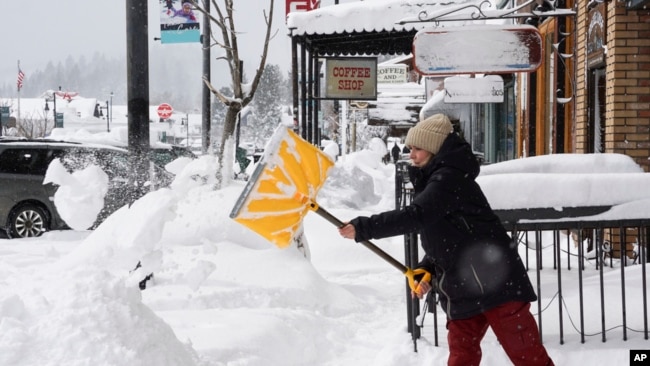 Residents clear sidewalks in front of businesses March 2, 2024, in downtown Truckee, Calif.