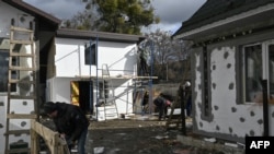 FILE — Workers rebuild a damaged house on Vokzalna street in Bucha, near Kyiv during the Russian invasion of Ukraine, Feb. 14, 2023.