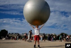 Harry Wilcznski poses for a picture in front of the cauldron with the Olympic flame in the Tuileries Gardens during the 2024 Summer Olympics, July 28, 2024, in Paris, France.