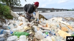 FILE—Residents collect plastics bottles and bags in the Ebrie Lagoon in Abidjan on May 31, 2023 ahead of World Environment Day celebrations. The United Nations Environment Program estimates that 400 million tons of plastic are produced worldwide each year.