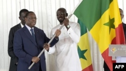 Le capitaine sénégalais Kalidou Koulibaly (à droite) reçoit le drapeau national sénégalais des mains du président sénégalais Macky Sall (à gauche), à Dakar, le 9 janvier 2024, avant le départ de l'équipe pour la Côte d'Ivoire. (Photo Seyllou / AFP)