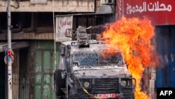 A Molotov cocktail explodes on an Israeli armored vehicle in clashes with Palestinians during an Israeli military raid in the old city of Nablus in the occupied West Bank.