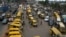Commuters walk next to parked public transport mini buses at Ojodu Berger bus station in Lagos, on June 1, 2023. Nigerians are lamenting the effect removal of the fuel subsidy is having on the economy, especially the massive hike in transport fare and cost of goods and services. 