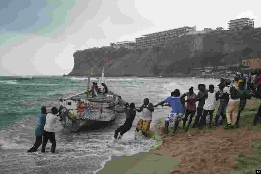 People pull, according to the locals, the capsized boat ashore at the beach where several people were found dead in Dakar, Senegal.