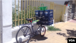 Con la ayuda de su amigo, Eduardo Parrello empieza a cargar sus productos en una bicicleta para comenzar el recorrido diario de la repartición