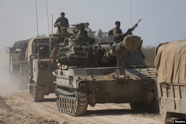 Israeli soldiers ride atop an artillery unit near the Israeli side of the border between Israel and the Gaza Strip, Nov. 3, 2023.