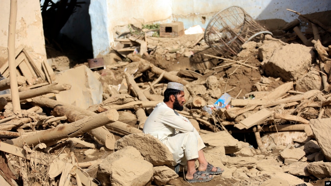 میدان ، وردک میں ایک شخص اپنے تباہ شدہ گھر کے سامنے بیٹھا ہے۔فوٹو اے پی