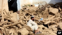 A man sits near his damaged home after heavy flooding in Maidan Wardak province in central Afghanistan, July 23, 2023.