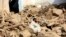 A man sits near his damaged home after heavy flooding in Maidan Wardak province in central Afghanistan, July 23, 2023.