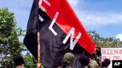 ARCHIVO - En esta fotografía de archivo del 12 de octubre de 1998, miembros del Ejército de Liberación Nacional (ELN) alzan su bandera en San Francisco, una región montañosa del norte de Colombia.