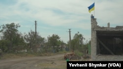 Ukrajinska zastava vijori se na spaljenoj prodavnici u selu koje je Ukrajina nedavno ponovo zauzela u Storoževu, Ukrajina, 23. juna 2023. (VOA/Yevhenii Shynkar)