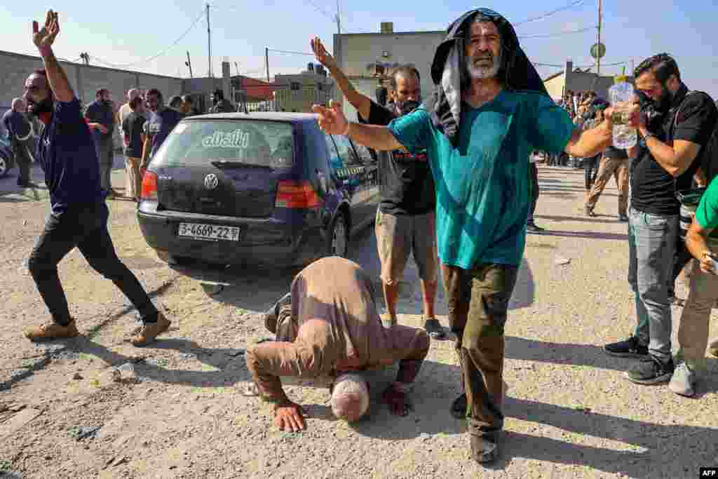 Palestinian workers, who were stranded in Israel since the October 7 attacks, react after crossing back into the Gaza Strip at the Kerem Shalom commercial border crossing with Israel in the south of the Palestinian enclave.
