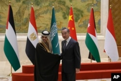 Chinese Foreign Minister Wang Yi, right, shakes hands with Saudi Arabia's Foreign Minister Faisal bin Farhan Al Saud at the Diaoyutai state guesthouse in Beijing, Nov. 20, 2023.