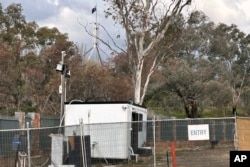 A flag on Australia's Parliament House flies behind where a fence surrounds a building on the grounds of a proposed new Russian embassy in Canberra, June 23, 2023.