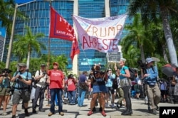 Trump supporters and protesters hold signs in front of the Wilkie D. Ferguson Jr. US Courthouse before the arraignment of former President Donald Trump in Miami, Florida, June 13, 2023.