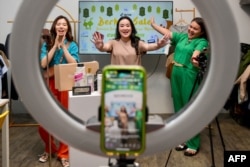 Monica Amadea (tengah), pemilik saluran penjualan TikTok bernama Monomolly, dan karyawannya menawarkan merchandise melalui streaming langsung TikTok di Jakarta. (Foto: AFP)