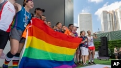 FILE - Participants hold the rainbow flag at the AIDS Quilt Memorial Ceremony ahead of the Gay Games in Hong Kong, Nov. 4, 2023.