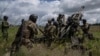 FILE - Ukrainian service members prepare to fire at Russian positions with a U.S.-supplied M777 howitzer in Kharkiv region, Ukraine, July 14, 2022.