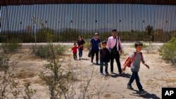 FILE - Migrants walk through the desert after crossing the border wall in the Tucson Sector of the U.S.-Mexico border, Aug. 29, 2023, near Lukeville, Ariz. 