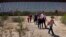 FILE - Migrants walk through the desert after crossing the border wall in the Tucson Sector of the U.S.-Mexico border, Aug. 29, 2023, near Lukeville, Ariz. 