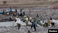 Para portir melintasi anak sungai sambil membawa barang-barang ke Iran di perbatasan Sulaymaniyah, Irak, 15 Februari 2012. (Foto: Reuters/Stringer)