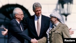 Predsjednik PLO-a Jaser Arafat rukuje se sa izraelskim premijerom Jicakom Rabinom dok američki predsjednik Bil Klinton stoji između njih, u Bijeloj kući, 13. septembra 1993. (Foto: Reuters/Gary Hershorn)