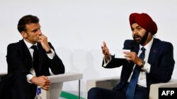French President Emmanuel Macron (L) looks on as he takes part in a round table discussion next to World Bank President Ajay Banga during the New Global Financial Pact Summit at the Palais Brongniart in Paris on June 22, 2023. 