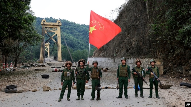FILE - Members of the Myanmar National Democratic Alliance Army pose with the group's flag in front of the Kunlong bridge in Shan state, Myanmar, Nov. 12, 2023. An offensive against the junta in Myanmar is helping China punish scammers.