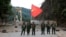 FILE - Members of the Myanmar National Democratic Alliance Army pose with the group's flag in front of the Kunlong bridge in Shan state, Myanmar, Nov. 12, 2023. An offensive against the junta in Myanmar is helping China punish scammers.