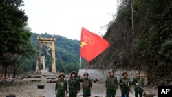 Miembros del Ejército de la Alianza Democrática Nacional de Myanmar posan con la bandera del grupo frente al puente Kunlong en el estado de Shan, Myanmar, el 12 de noviembre de 2023. Una ofensiva contra la junta en Myanmar está ayudando a China a castigar a los golpistas.