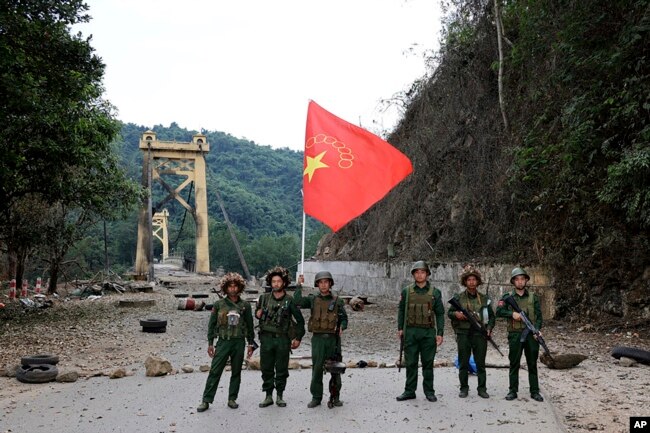 FILE - Members of the Myanmar National Democratic Alliance Army pose with the group's flag in front of the Kunlong bridge in Shan state, Myanmar, Nov. 12, 2023.