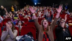People react as they watch a parliament session on a confidence vote of outgoing Polish prime minister Mateusz Morawiecki, in a cinema in Warsaw.&nbsp;