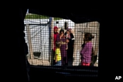 Syrian women and their children, seen through a tent window, stand at a refugee camp in the town of Bar Elias, in Lebanon's Bekaa Valley, June 13, 2023.