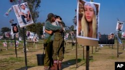 Israeli soldiers embrace next to photos of people killed and taken captive by Hamas militants Oct. 7, near kibbutz Re'im, Dec. 1, 2023.