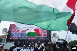 Seorang perempuan mengibarkan bendera Palestina dalam aksi unjuk rasa di Jakarta, Senin, 20 Maret 2023, memprotes partisipasi tim Israel di Piala Dunia FIFA U-20 di Indonesia. (AP/Achmad Ibrahim)