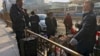 资料照片: 2023年1月6日北京: 带着行李的农民工乘火车前在西站外休息